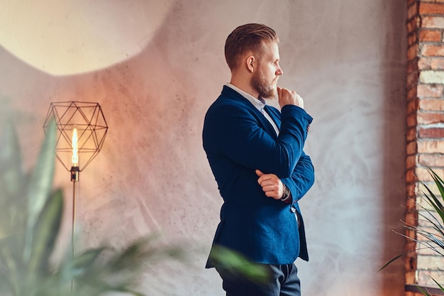 Un hombre moderno y elegante vestido con un elegante traje posando en una habitación con interior tipo loft.