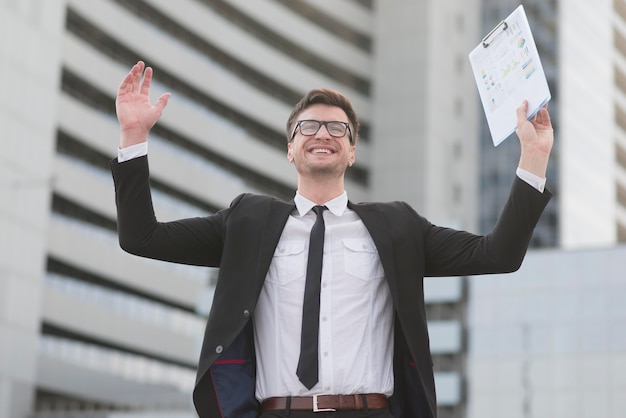 Hombre moderno feliz de ángulo bajo con portapapeles