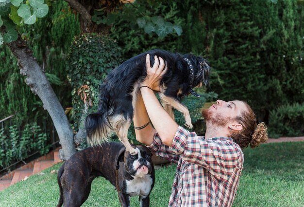 Hombre moderno jugando con perros en jardín