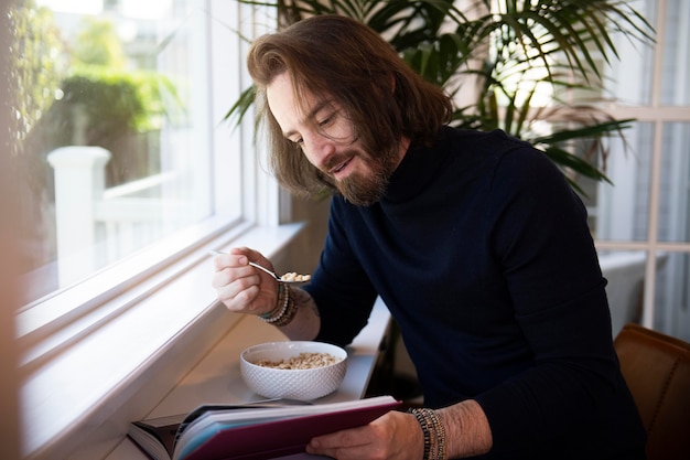 Foto gratuita hombre moderno leyendo mientras desayuna