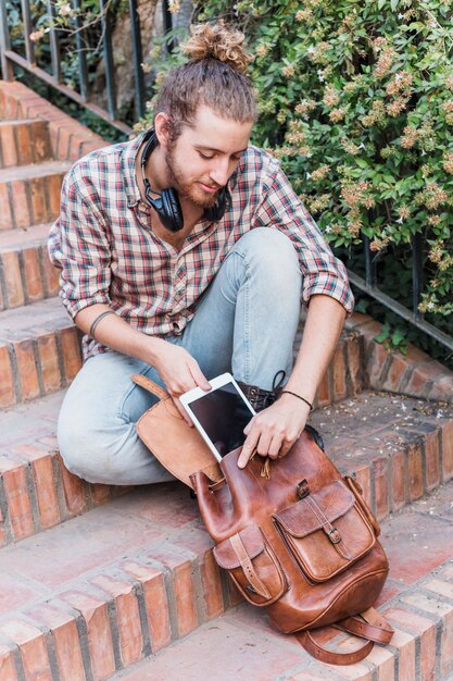 Hombre moderno poniendo tableta en mochila