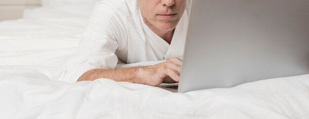 Hombre moderno senior usando una computadora portátil en la cama