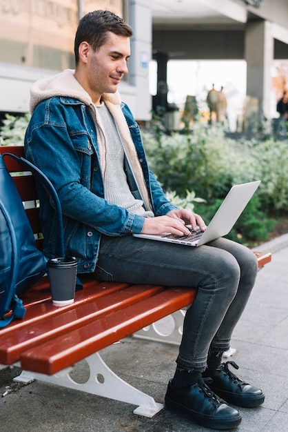 Hombre moderno sentado en banco en entorno urbano