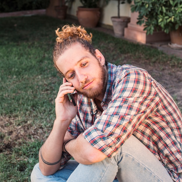 Hombre moderno con smartphone en jardín