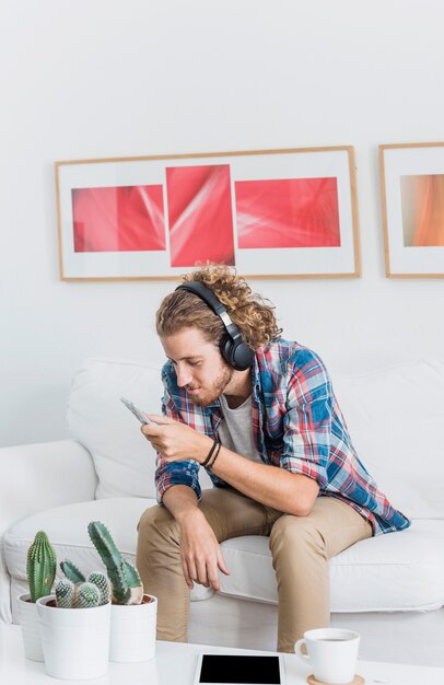 Hombre moderno con smartphone en sofá