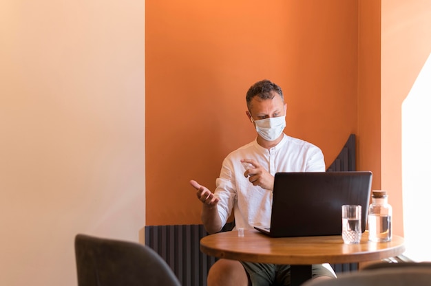 Hombre moderno trabajando con su máscara médica y desinfectando sus manos