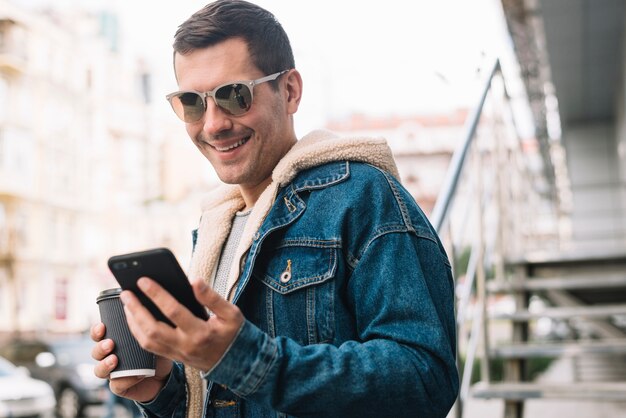 Hombre moderno usando smartphone en ciudad