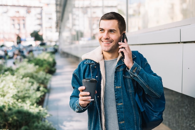 Hombre moderno con vaso de café en entorno urbano