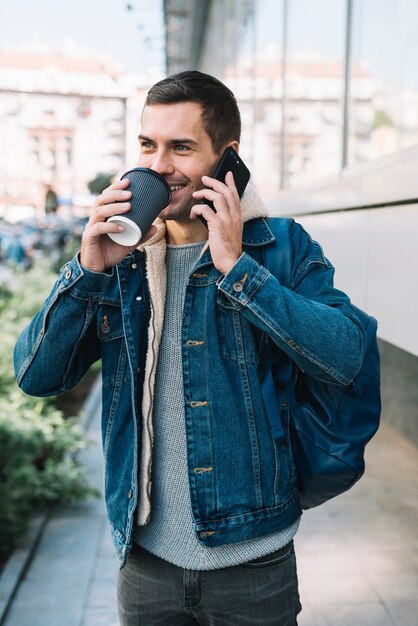 Hombre moderno con vaso de café en entorno urbano