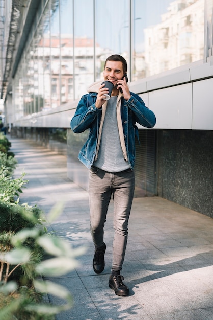 Hombre moderno con vaso de café en entorno urbano