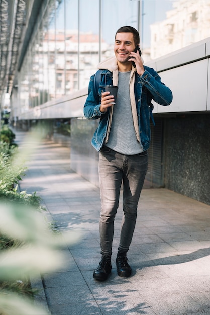 Hombre moderno con vaso de café en entorno urbano