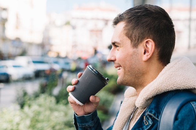 Hombre moderno con vaso de café en entorno urbano