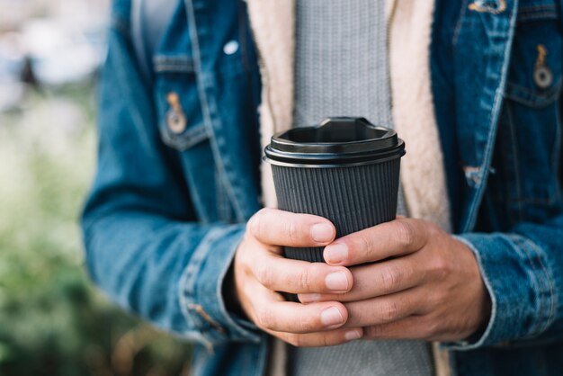 Hombre moderno con vaso de café en entorno urbano