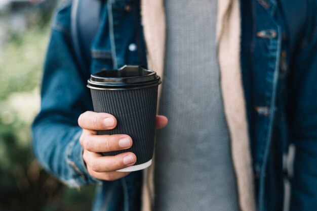 Hombre moderno con vaso de café en entorno urbano