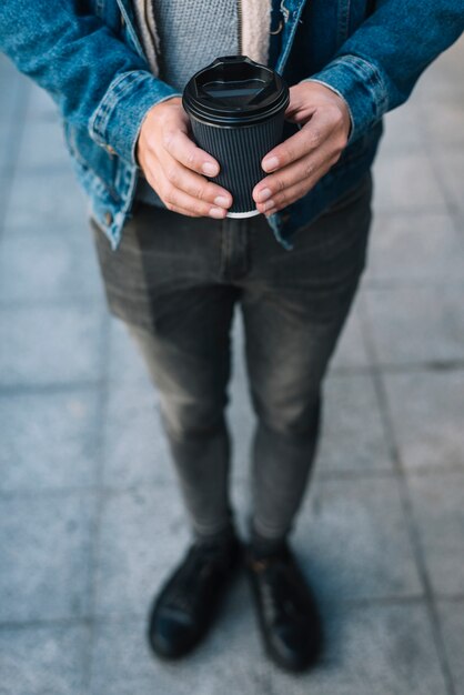 Hombre moderno con vaso de café en entorno urbano