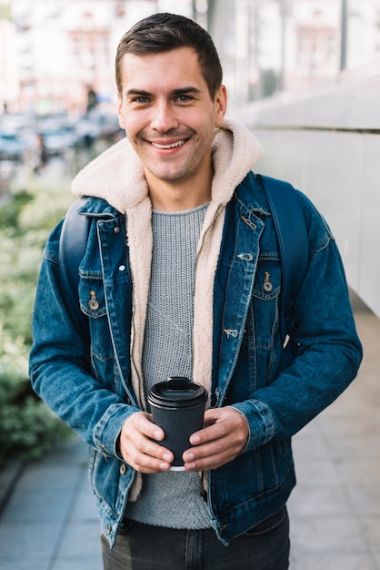 Hombre moderno con vaso de café en entorno urbano