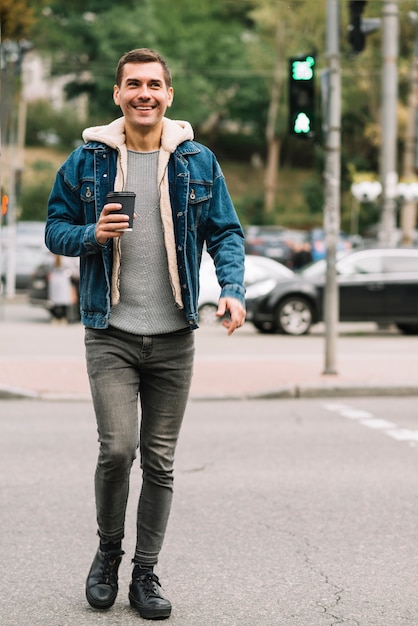 Hombre moderno con vaso de café en entorno urbano