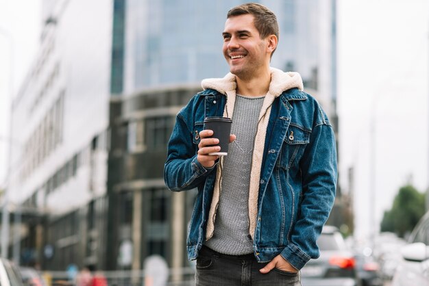 Hombre moderno con vaso de café en entorno urbano