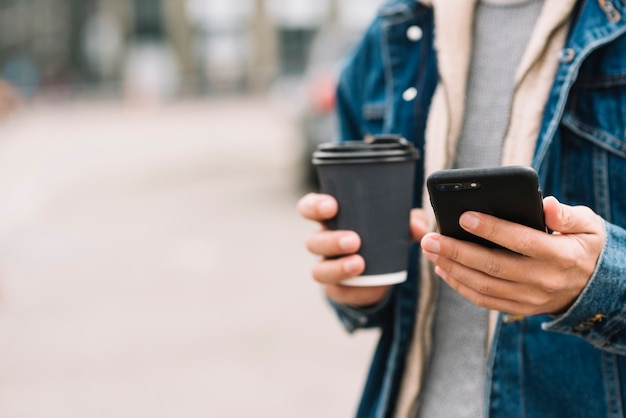 Hombre moderno con vaso de café en entorno urbano