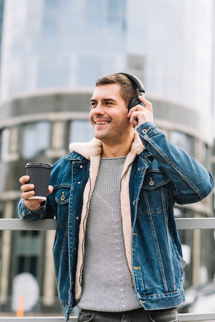 Hombre moderno con vaso de café en entorno urbano