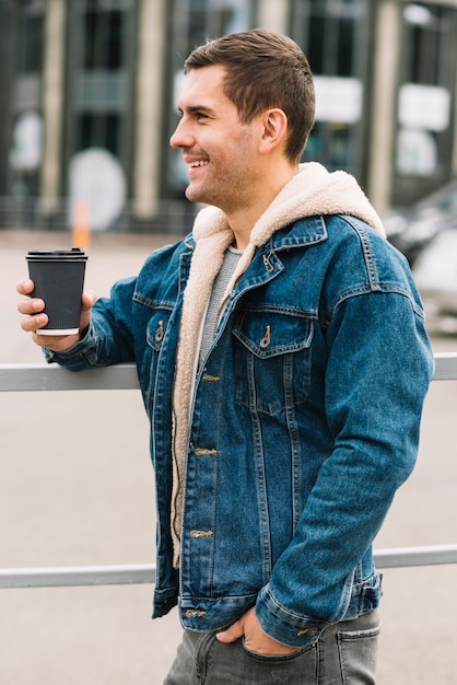 Hombre moderno con vaso de café en entorno urbano