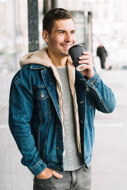 Hombre moderno con vaso de café en entorno urbano