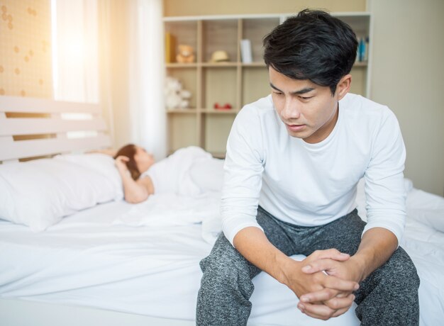 Hombre molesto que tiene problemas para sentarse en la cama después de discutir con su novia