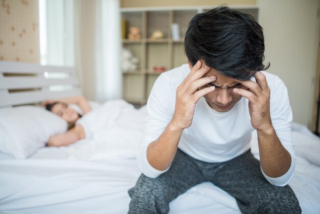 Hombre molesto que tiene problemas para sentarse en la cama después de discutir con su novia