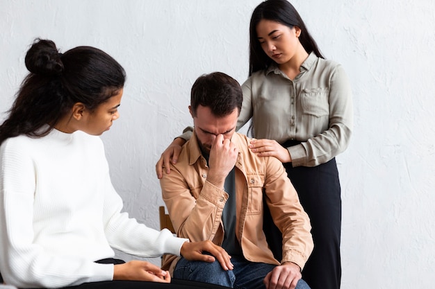 Foto gratuita hombre molesto siendo consolado en una sesión de terapia de grupo