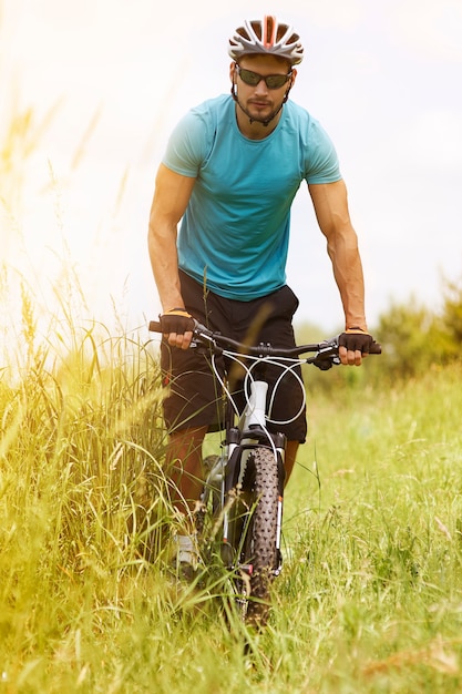 Hombre montado en su bicicleta por la pradera