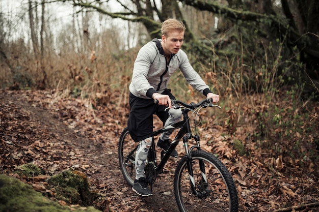 Hombre montando bicicleta en el bosque durante el otoño