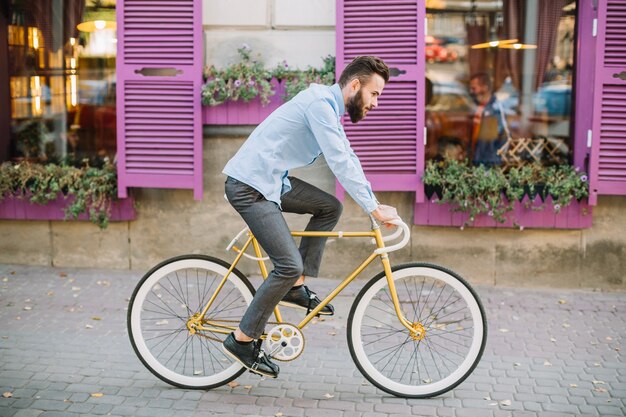 Hombre montando bicicleta cerca de ventanas rosas