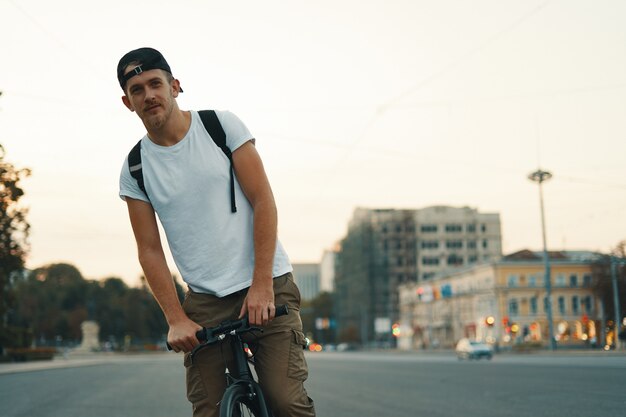 Hombre montando bicicleta en la ciudad urbana de la mano en el manillar