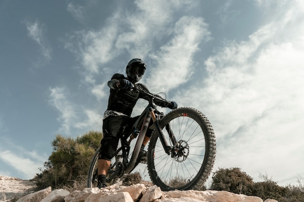 Foto gratuita hombre montando una bicicleta de montaña en ángulo bajo