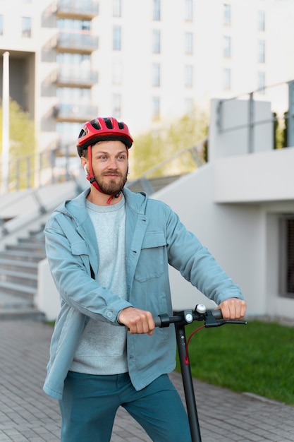 Hombre montando un scooter ecológico en la ciudad.