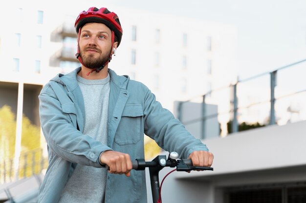 Hombre montando un scooter ecológico en la ciudad.