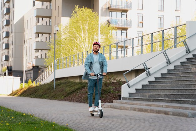 Hombre montando un scooter ecológico en la ciudad.