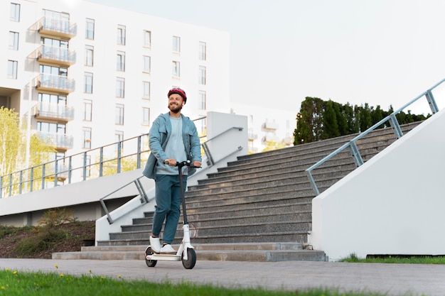 Hombre montando un scooter ecológico en la ciudad.