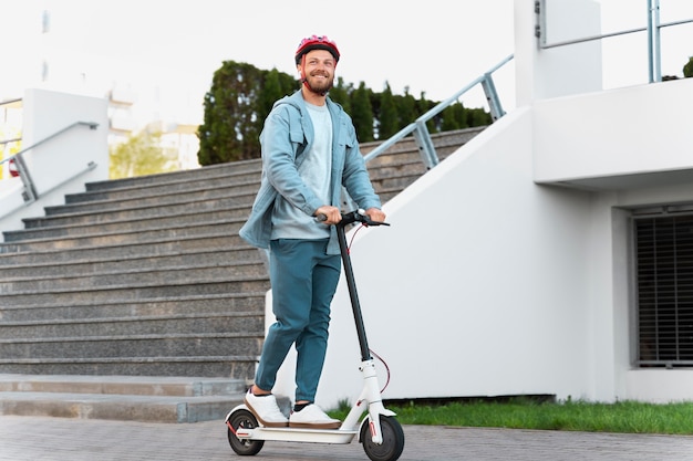 Hombre montando un scooter ecológico en la ciudad.