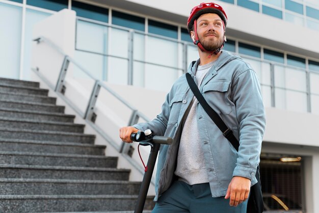 Hombre montando un scooter ecológico en la ciudad.