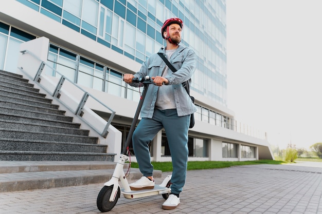 Hombre montando un scooter ecológico en la ciudad.