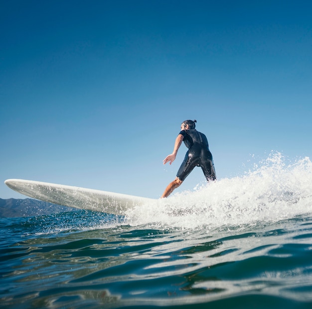 Hombre montando su vista lateral de la tabla de surf