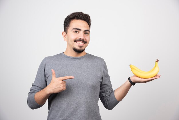 Hombre morena apuntando al plátano en gris.