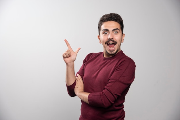 Un hombre morena feliz mostrando un dedo hacia arriba y posando.