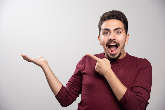 Un hombre morena sonriente apuntando a su mano.