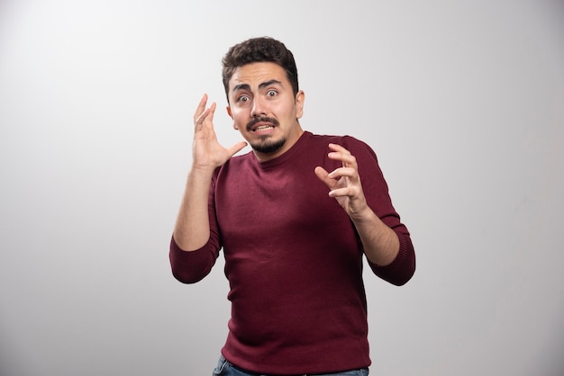 Un hombre morena sorprendido posando con las manos.