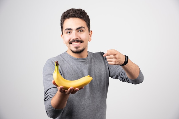 Hombre morena sosteniendo plátano y apuntando a él.