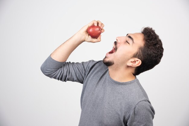 Hombre morena tratando de comer manzana roja.