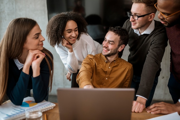 Foto gratuita hombre mostrando algo a sus colegas en la computadora portátil durante una reunión