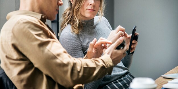 Hombre mostrando algo en un teléfono inteligente a una mujer